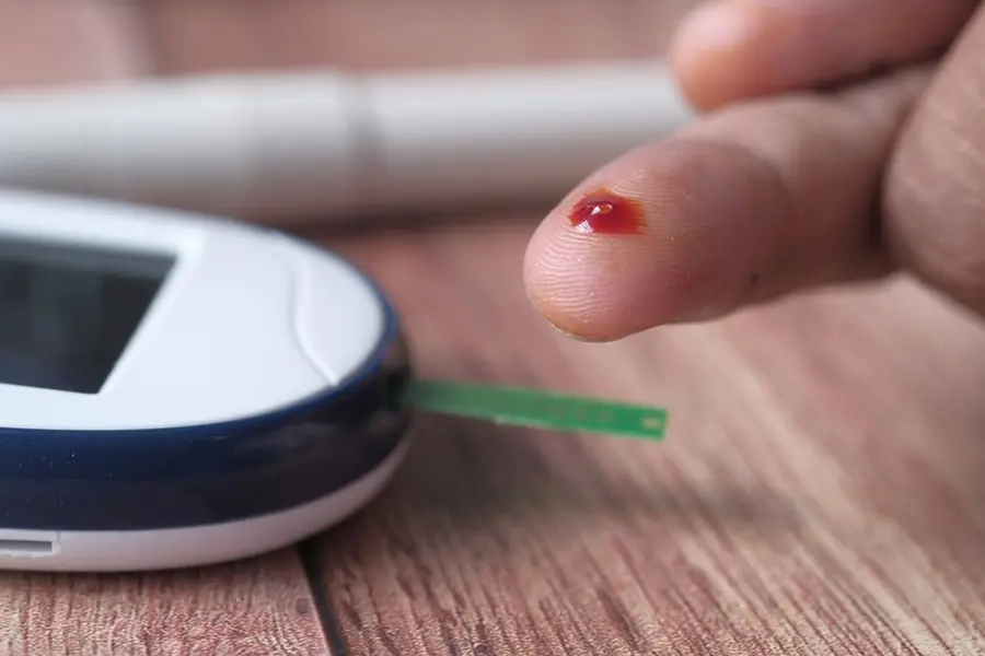 Person using a fingerstick blood glucose meter at home to check their blood sugar