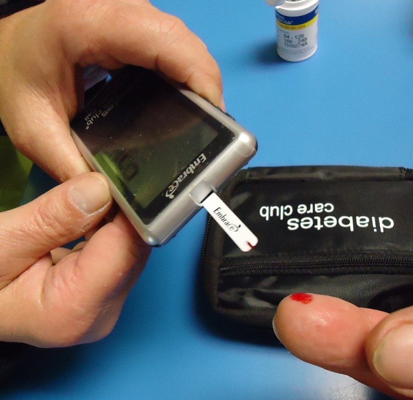 person testing blood sugar with glucose meter at home